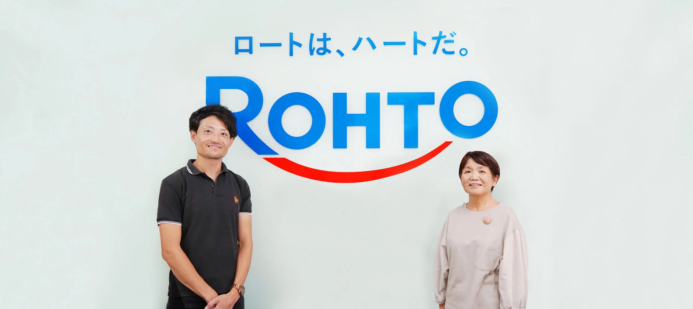 キャッチコピー“ロートは、ハートだ。”とROHTOのロゴを背景に、男性と女性が左右に並んで微笑んでいる