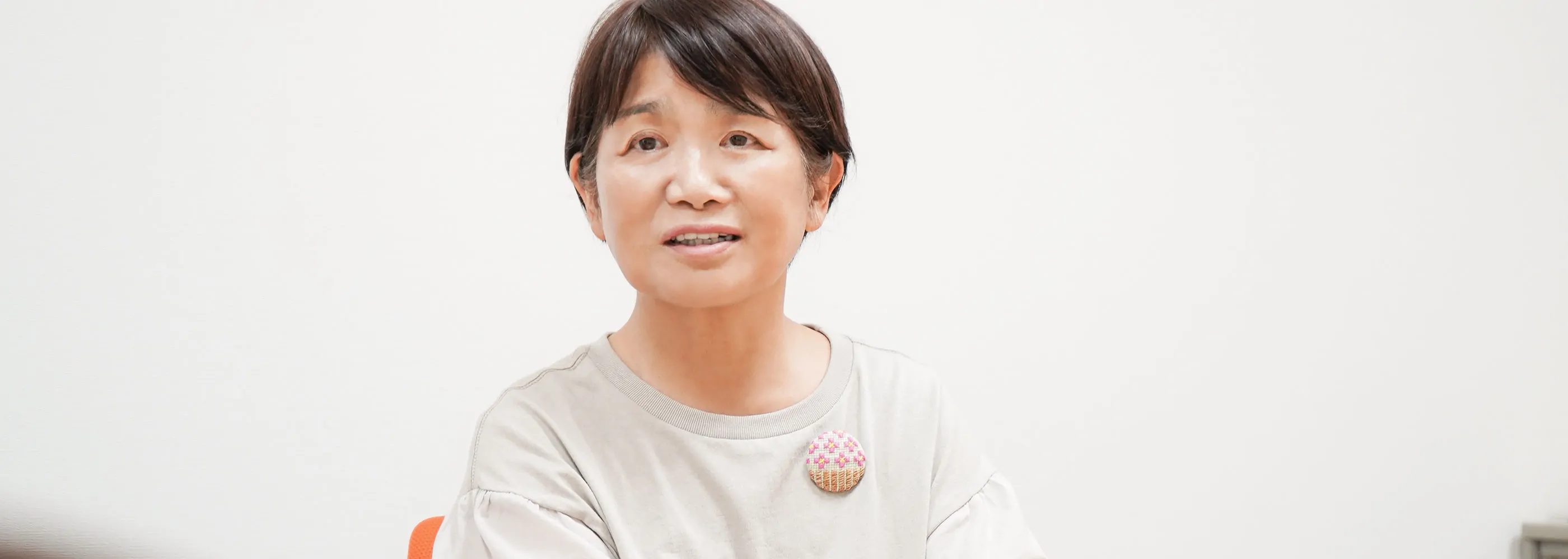 白いオフィスで淡色トップスの女性が微笑みながら話すインタビュー風景